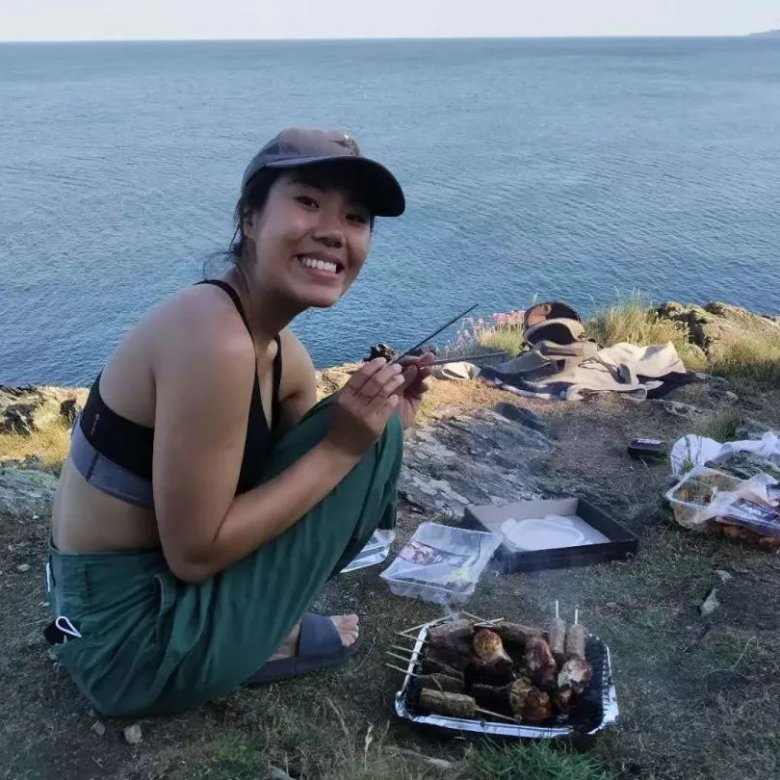 A woman in a cap smiling while crouched down on above the sea