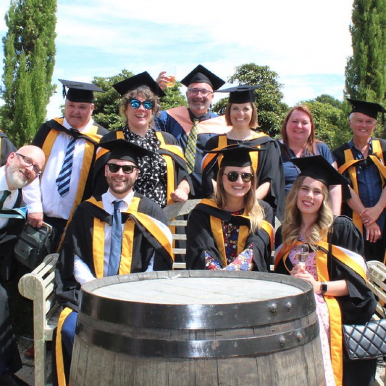 A group of graduating students wearing gowns gather together