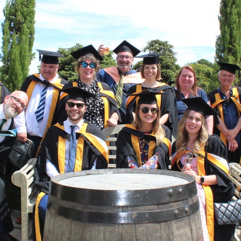 A group of graduating students wearing gowns gather together 