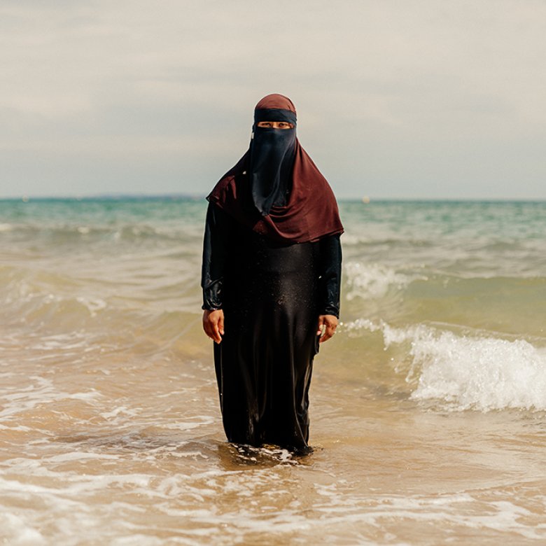 Woman wearing hijab standing in the sea. Portrait of Britain 2023 winning photo by Peter Flude. 