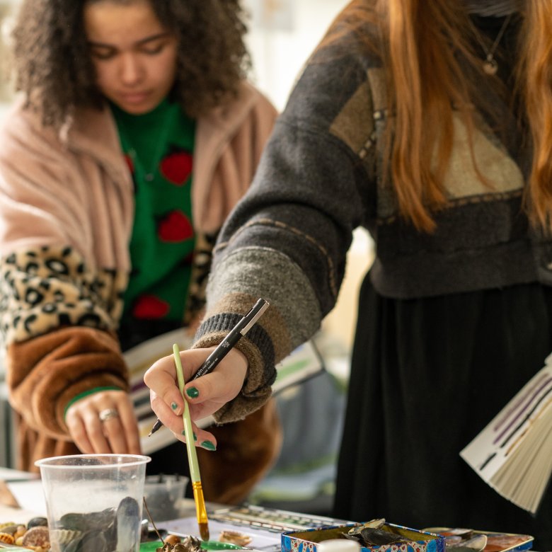 A photograph of two students with paintbrushes