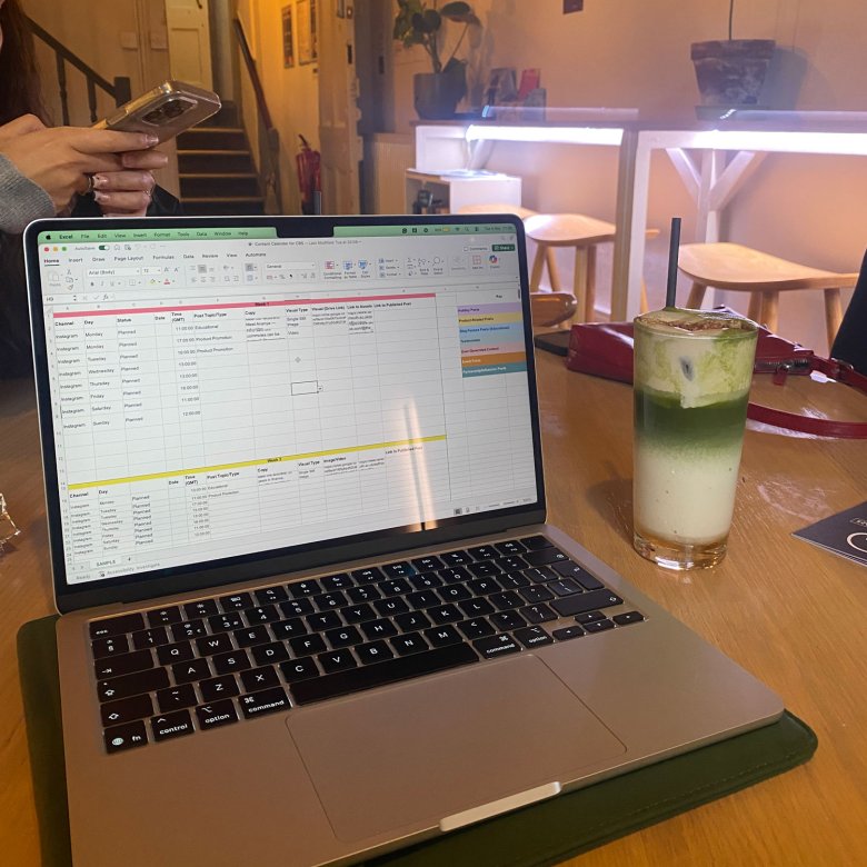 A laptop with excel open and a drink next to it