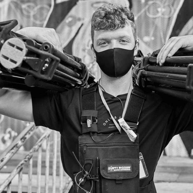 A student holds camera tripods on a tv set 