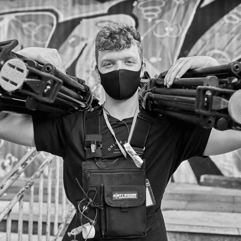 A student holds camera tripods on a tv set 