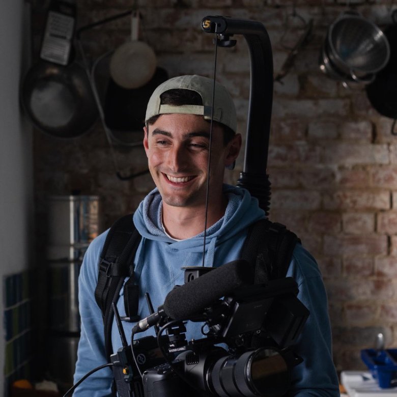 A young man in a backwards cap holding a large camera