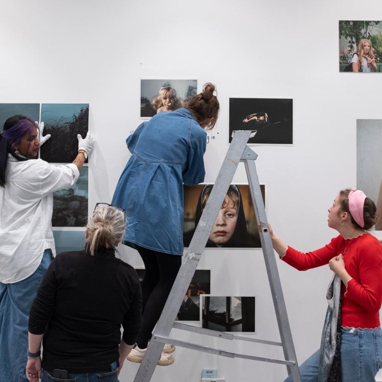 Four people hanging a photography exhibition
