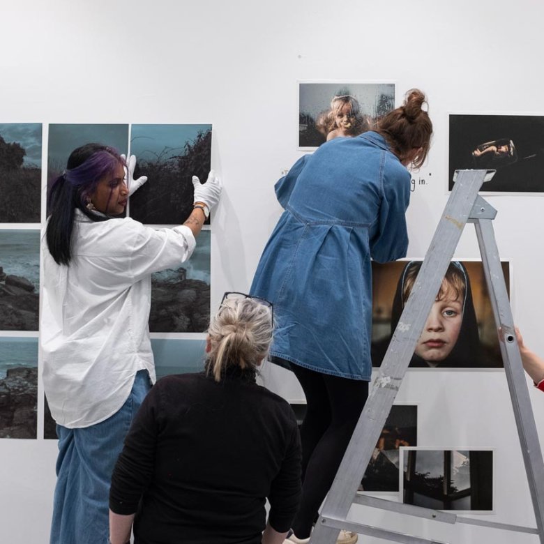 Four people hanging a photography exhibition