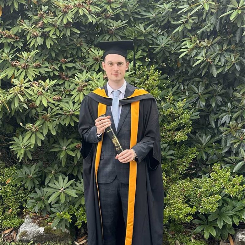 User Experience Design graduate Paul Phillips at graduation wearing a gown and mortar board