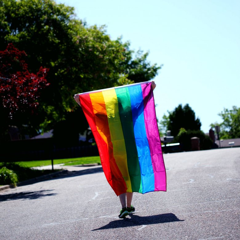 A pride flag is draped over shoulders