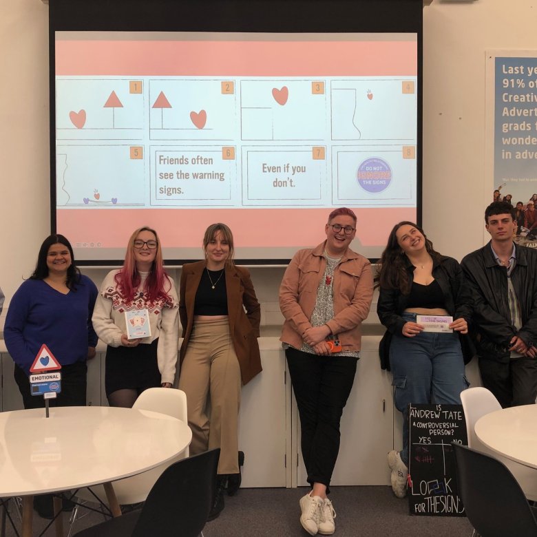 A group of Creative Advertising student standing in front of a screen in a seminar room