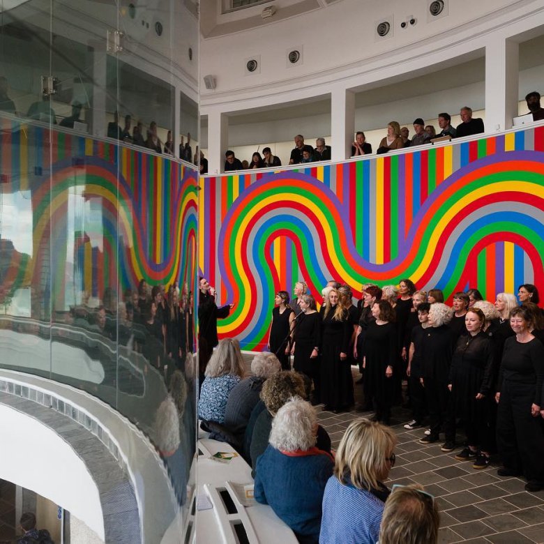 Line of people wearing black infront of rainbow background at Tate St Ives