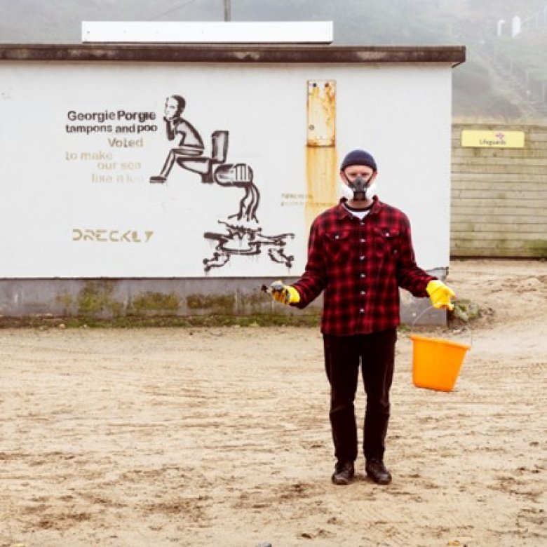 Sustainable Product Design graduate Niall Jones wearing mask and carrying a bucket on Porthtowan beach as part of SAS Floater campaign.