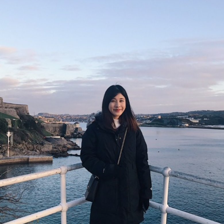 A woman poses in front of the ocean