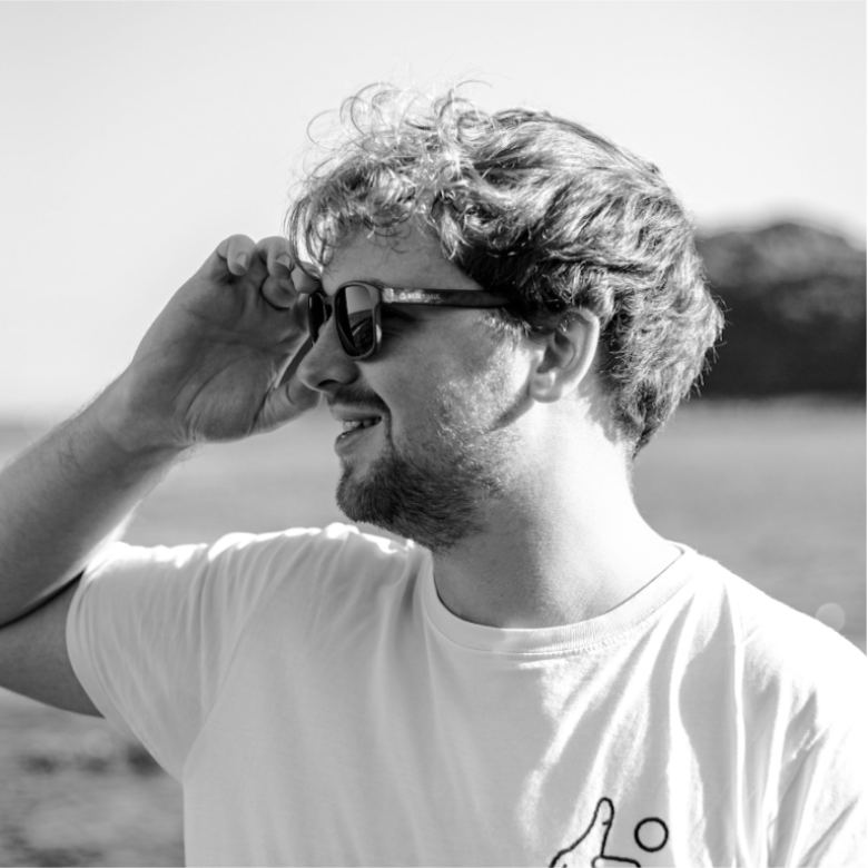 A man looks to his left, wearing sunglasses. The picture is in black and white