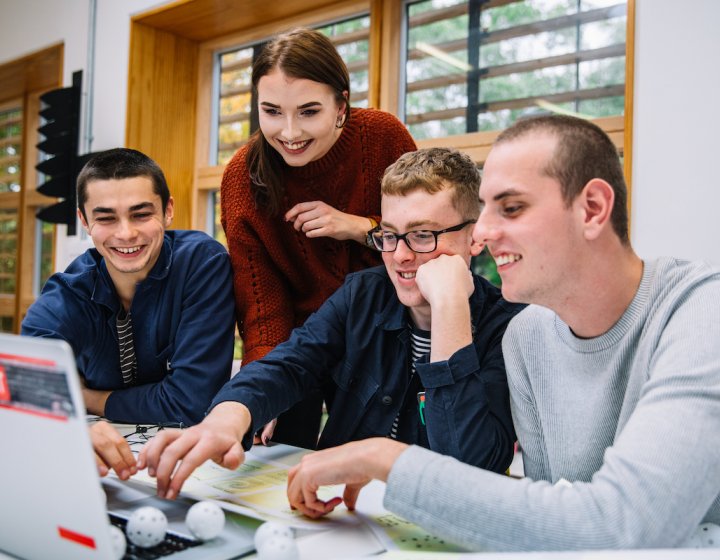 Thee male students and one female student around a laptop