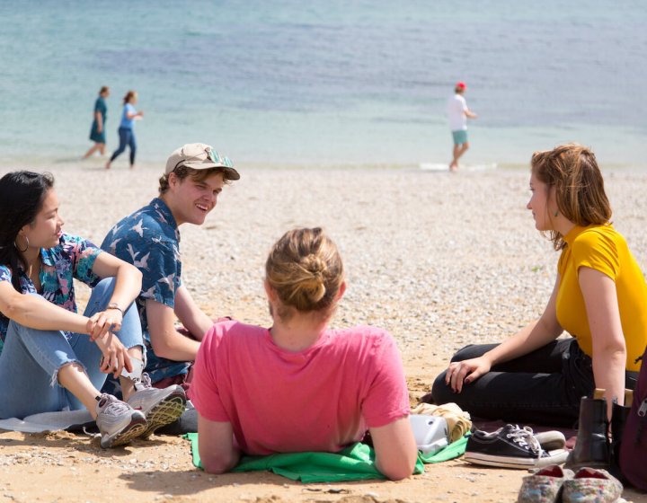 Falmouth University students relaxing on the beach