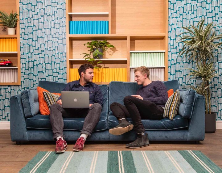 Falmouth advertising alumni Ben Fallows and Matt Deacon chatting on a sofa.