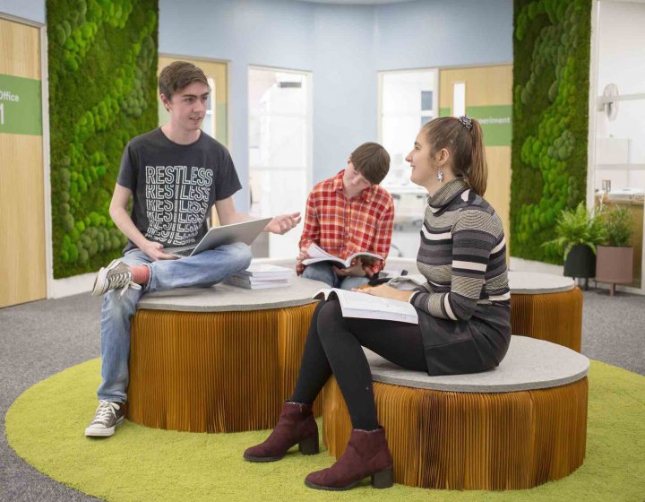 Three Business students sitting on brown seats, talking