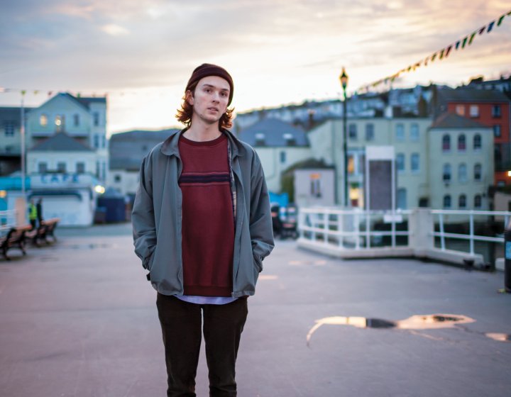 Student on pier in Falmouth with skateboard.