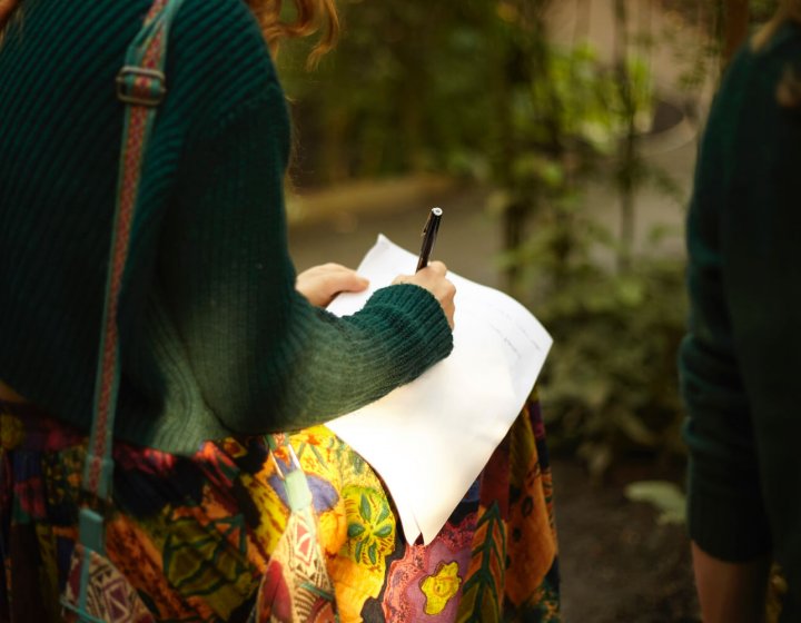 A girl in a green jumper writing on white paper