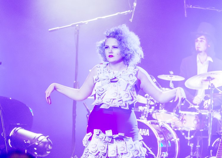 Actor on stage with band lit with purple light.