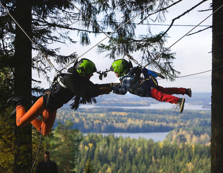 A man and child on a zip wire with trees