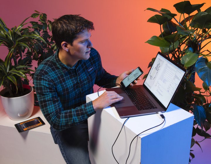 A male student working on a laptop with plants