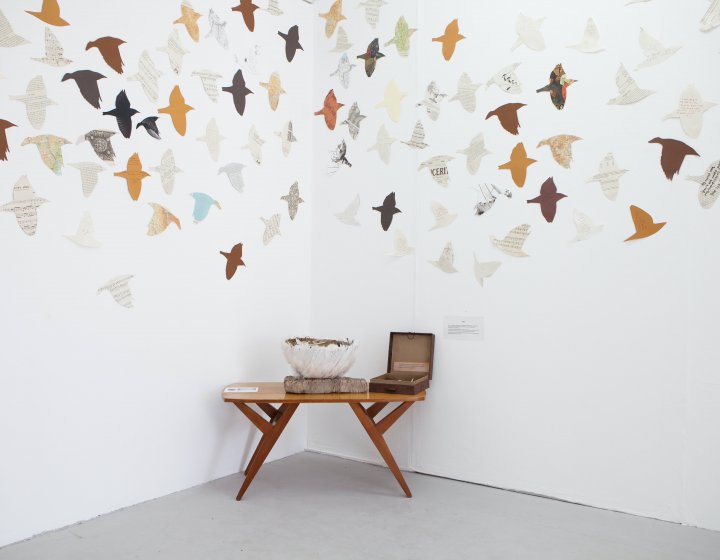 A bowl and small box on a table with cut out birds on the wall