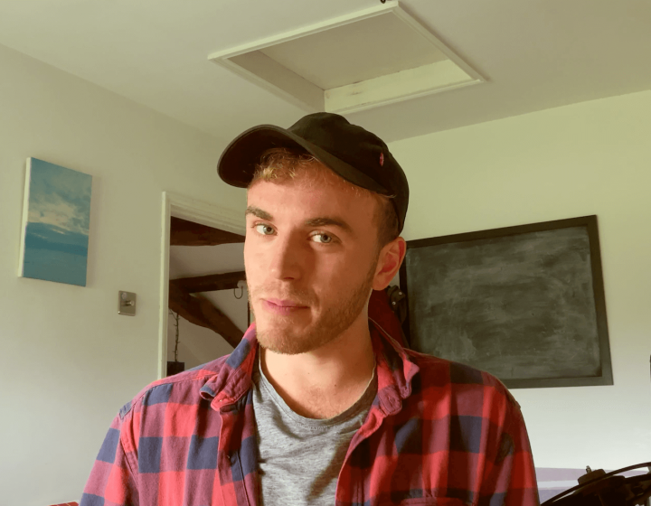 A Falmouth University student wearing a baseball cap and red checked shirt