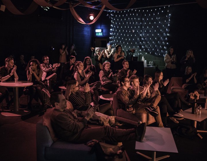 An audience sat around tables at an event