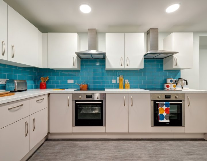 Kitchen interior with white cupboards and teal coloured tiles