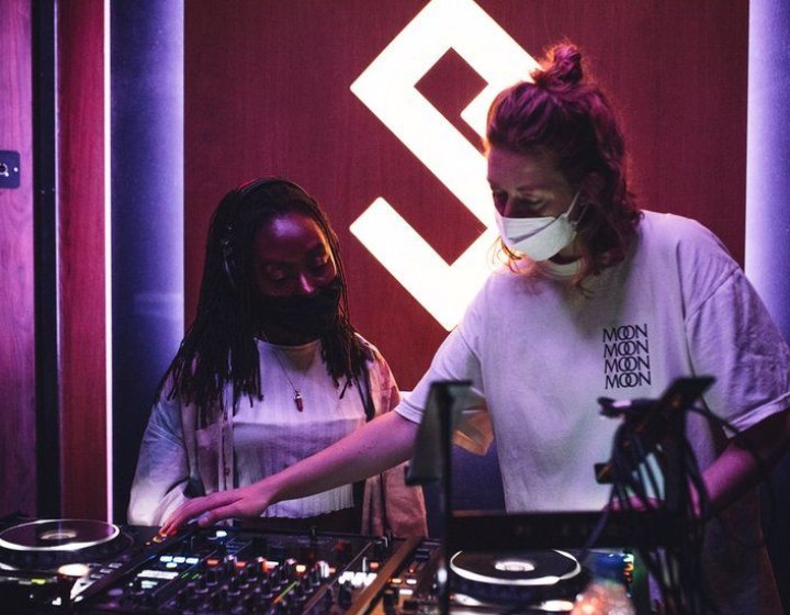 Graduate DJ Daisy Moon at the decks with another woman.