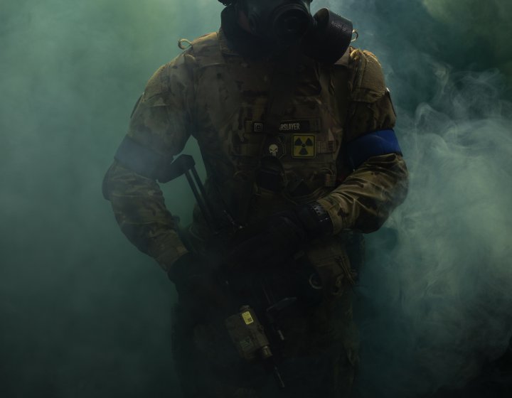 An airsoft player emerging from smoke