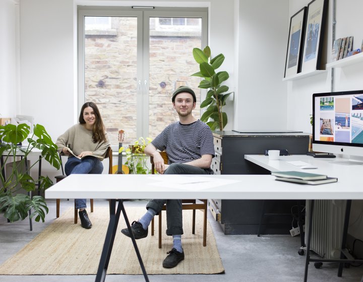 Artists sat in studio looking at camera.