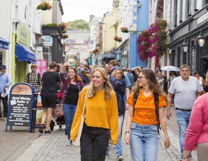 Two students dressed in orange tops walking along Falmouth high street