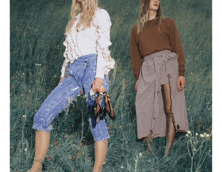Two female fashion models in a field, wearing Jeans and a skirt