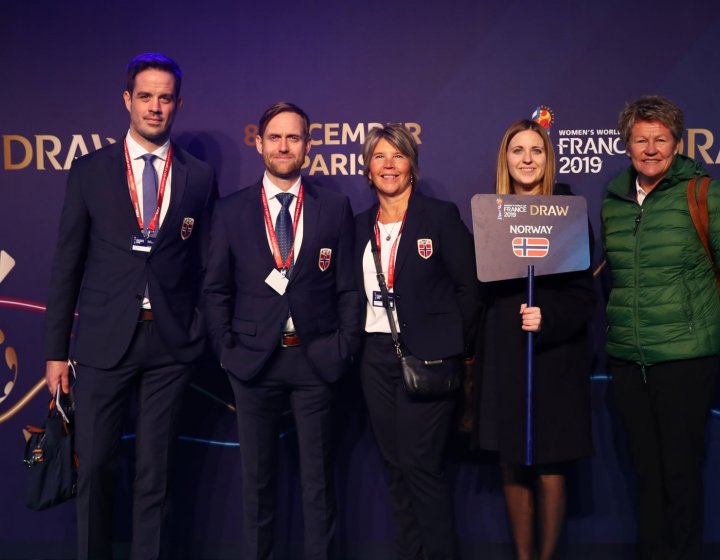 Five people standing in front of a purple wall with France 2019 FIFA