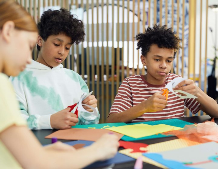 Young adults cutting out pieces of coloured paper