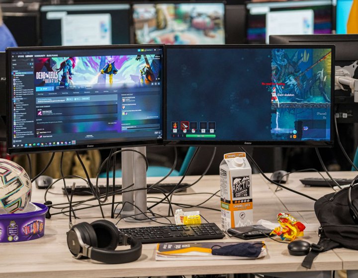 A computer is surrounded by coffee and sweets 