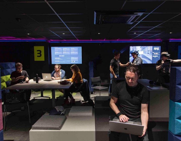 students sitting in a games studio with screens at Falmouth University
