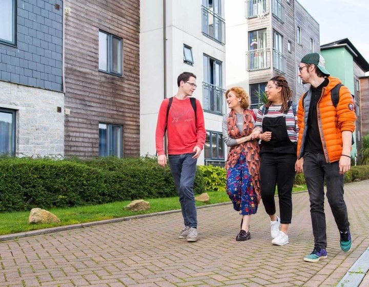 Students walking through Glasney Village with arms linked.