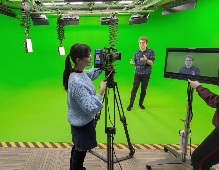 Falmouth students working camera and viewing a screen in a green studio.