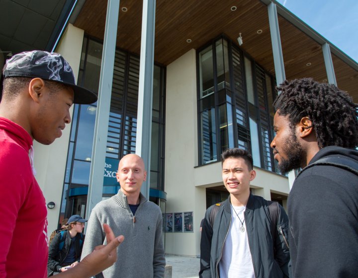 Students in a group talking outside the exchange at Penryn campus.