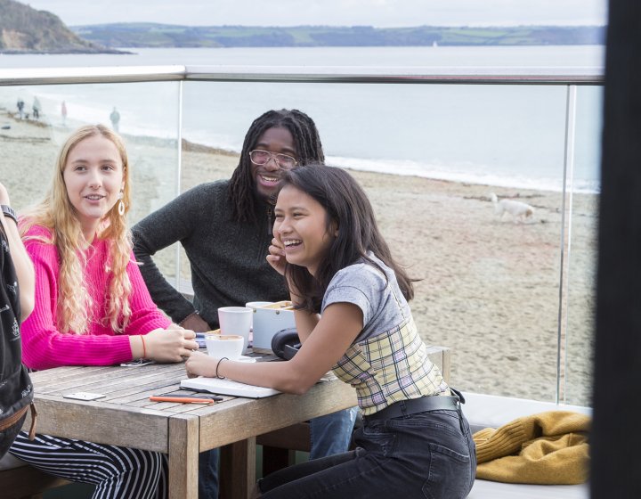 students sat outside on a bench overlooking the sea