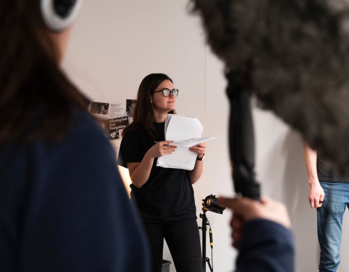 Film student standing holding pieces of paper