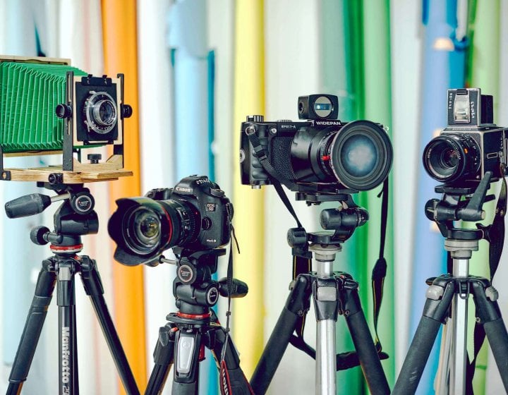 Four cameras on tripods in front of a colourful background