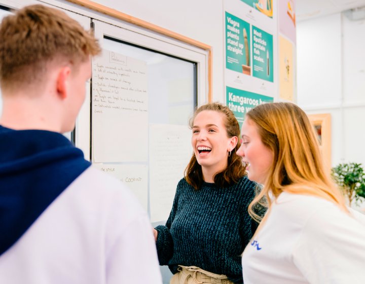 Three creative advertising students talking while standing