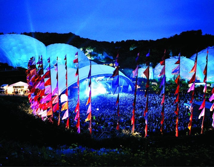 A gig at Eden Project at night surrounded by colourful silk flags.