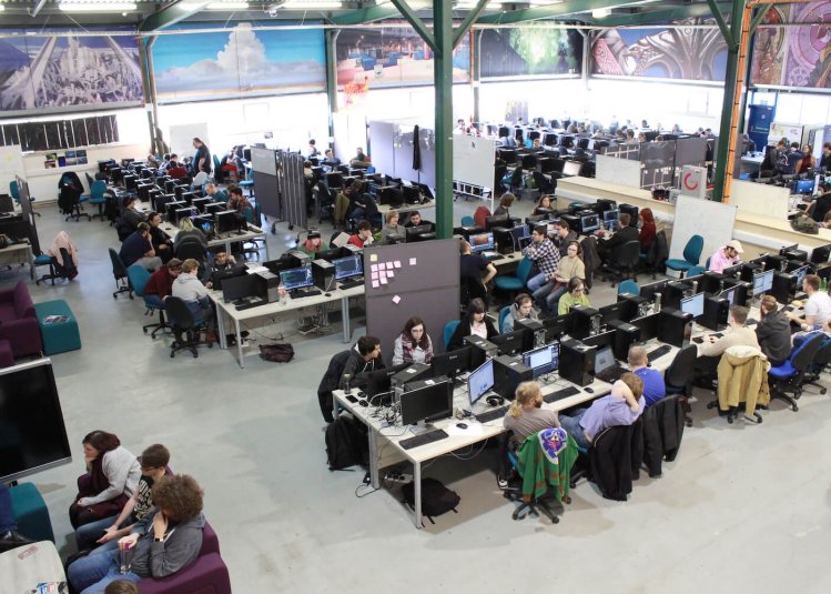 A large warehouse full of gaming students at computers and computer artwork on the walls