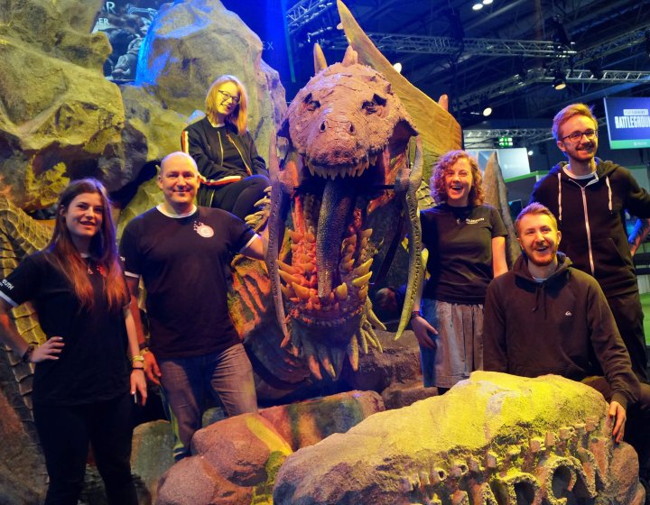 Falmouth University Games Academy students standing in front of a large dinosaur model